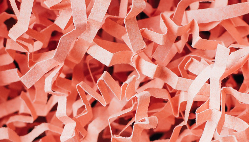 Peach-colored shredded paper Easter basket filler.